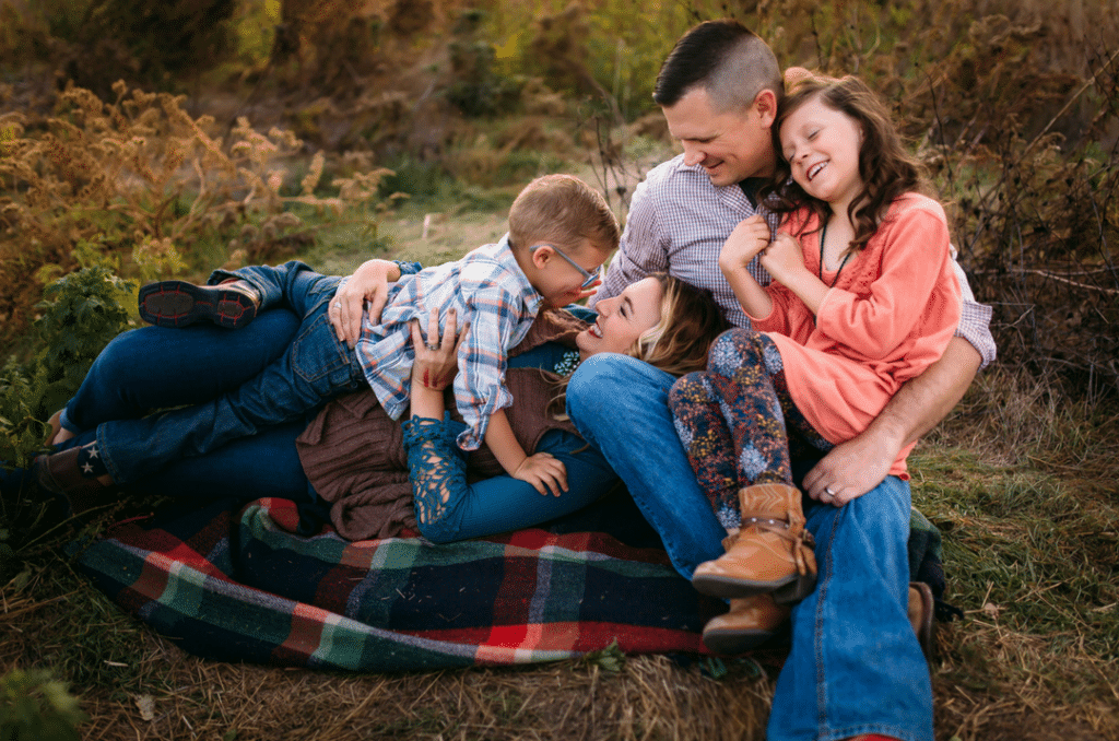 A family is laying on a blanket in the grass.