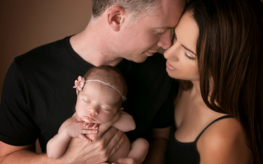 A man and a woman are holding a newborn baby.