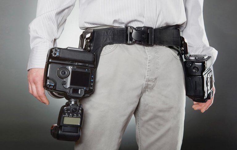 A man is carrying two cameras on his belt.