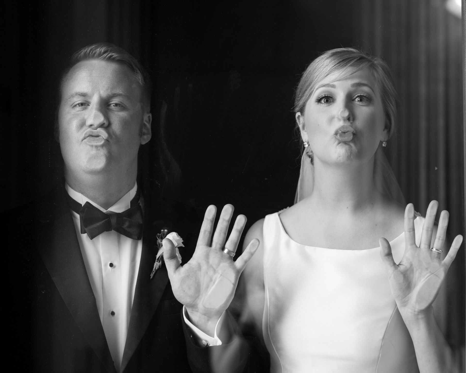 A black and white photo of a bride and groom making funny faces.