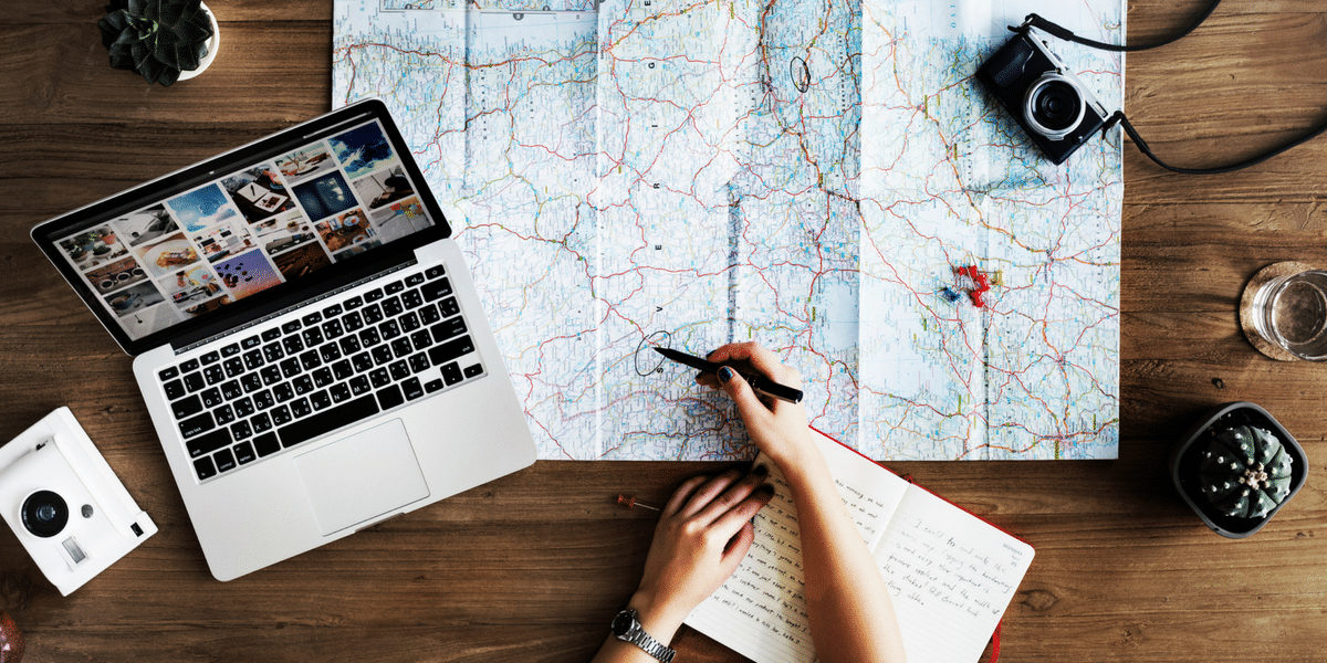 A person is sitting at a table with a laptop and a map.