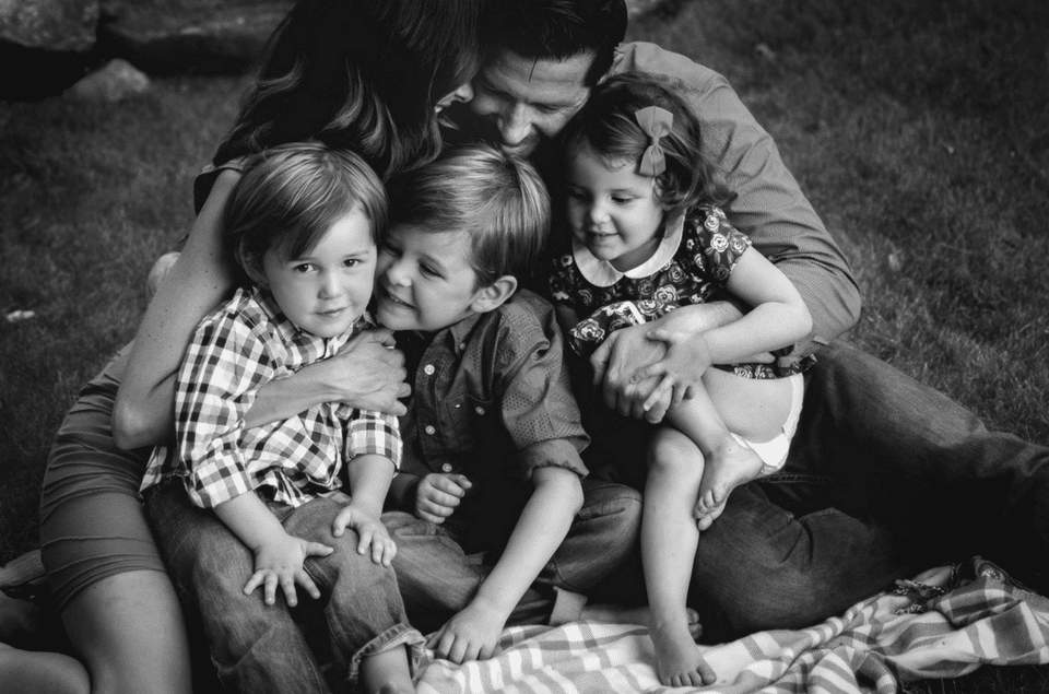 A black and white photo of a family sitting on a blanket.