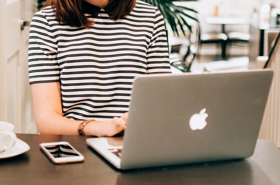 A woman is sitting at a table using a laptop computer.