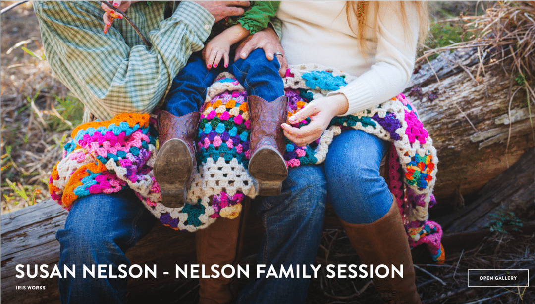 A family is sitting on a log with a colorful blanket.