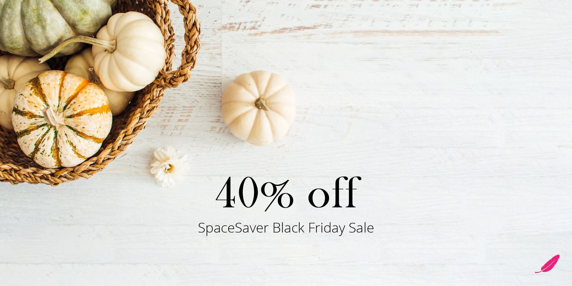 A basket of pumpkins is sitting on a white wooden table.