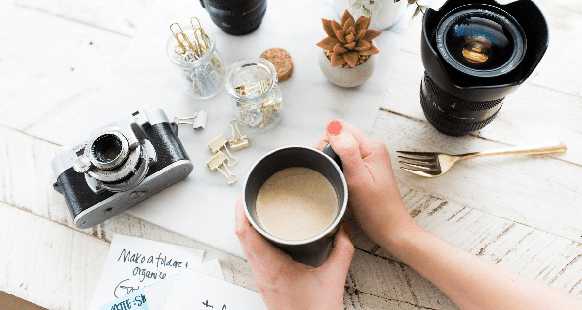 A person is holding a cup of coffee on a table.