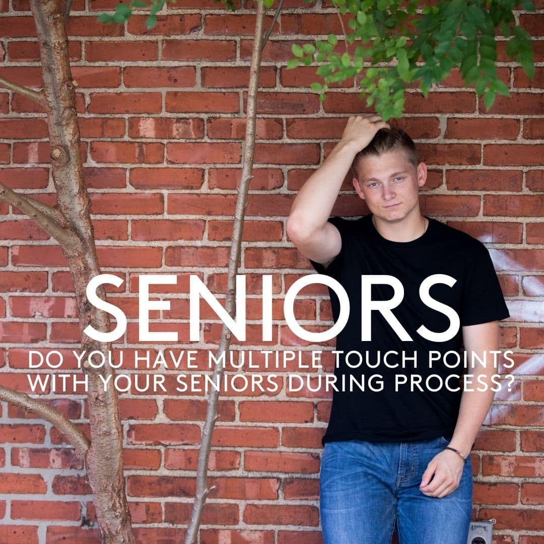 A man standing in front of a brick wall with the words seniors on it