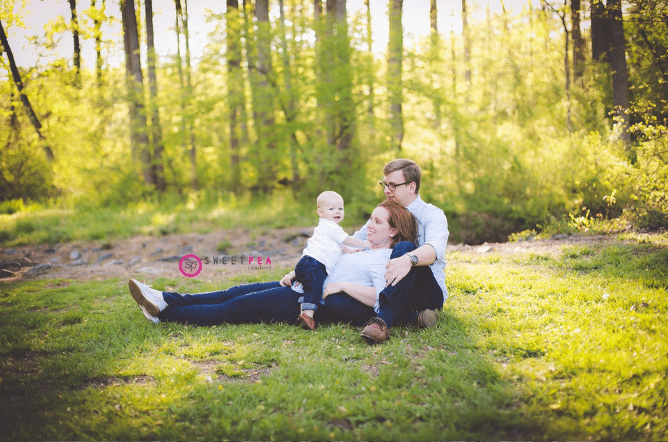 A family is sitting on the grass in the woods.