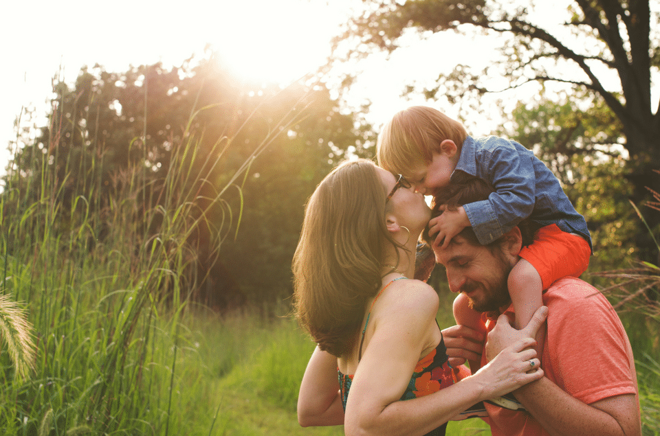 A man is carrying a child on his shoulders in a field.