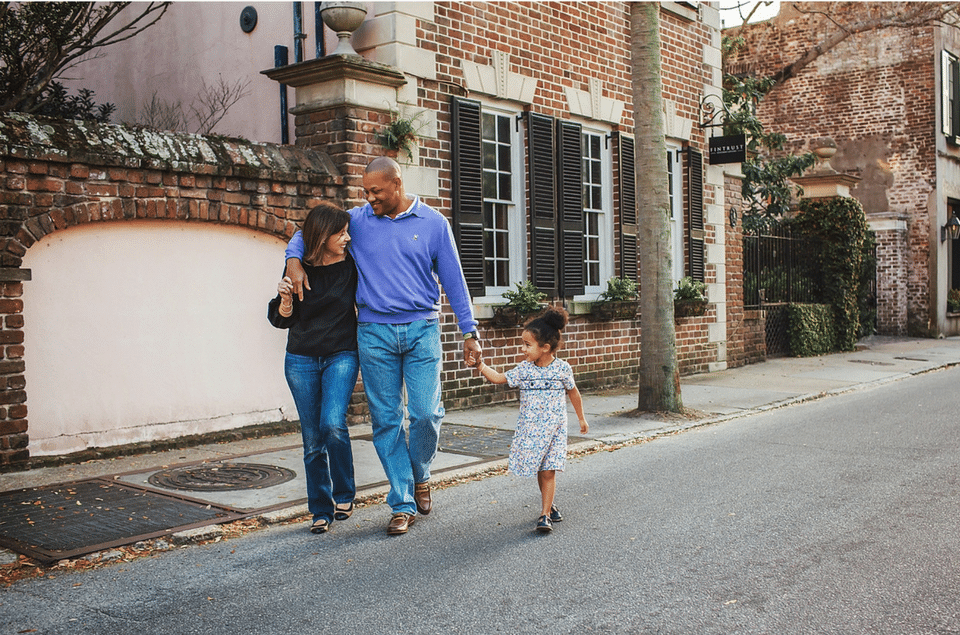 A family is walking down the street holding hands.