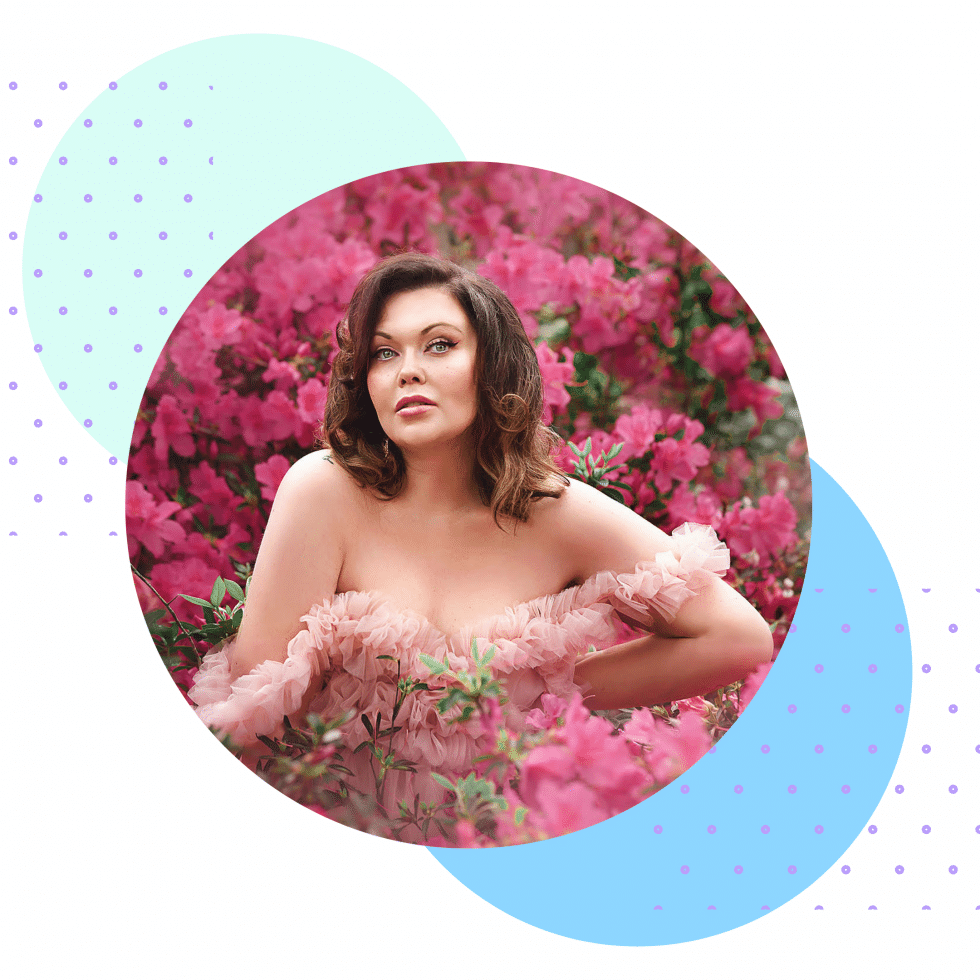 A woman in a pink dress is standing in a field of pink flowers.