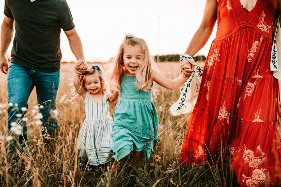 A family is holding hands while walking through a field.