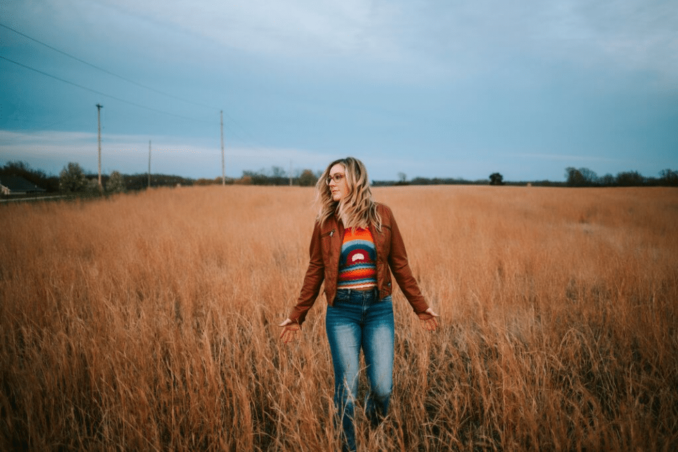 A woman is walking through a field of tall grass.