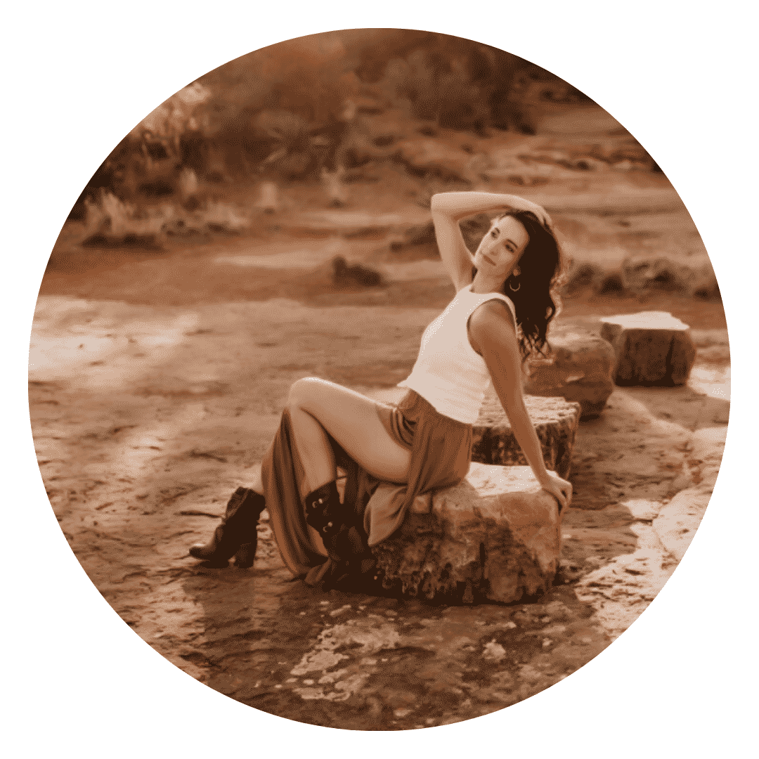 A woman is sitting on a rock with her legs crossed