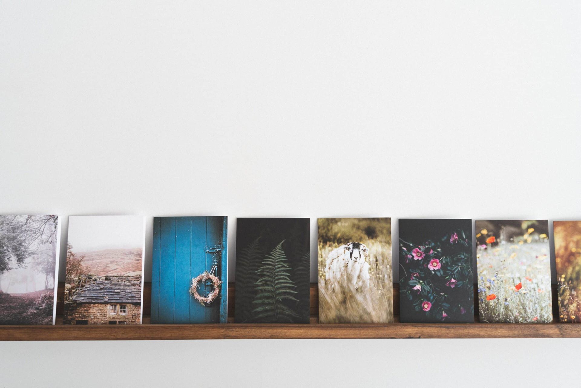 A wooden shelf with a row of pictures on it.