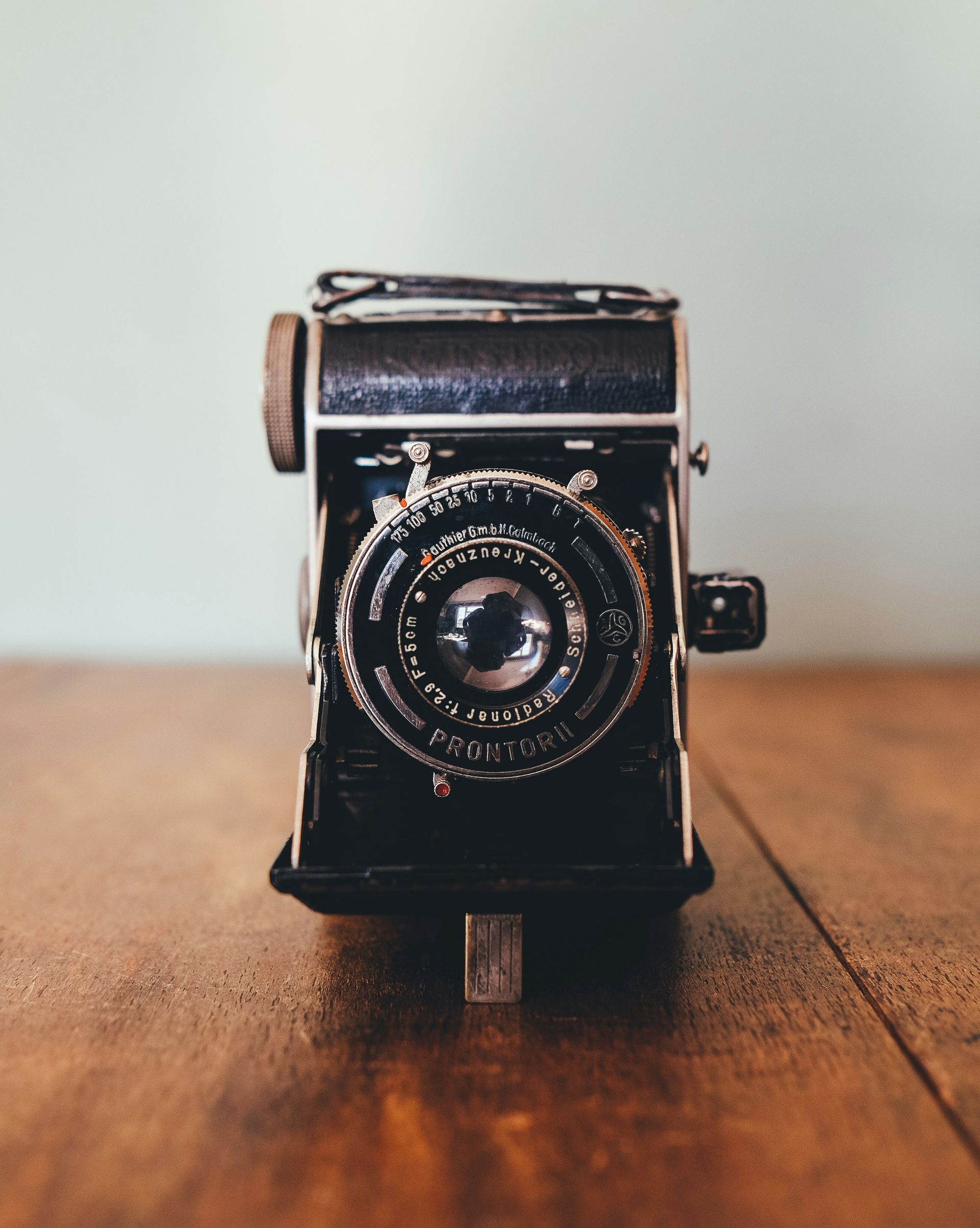 An old camera is sitting on a wooden table.