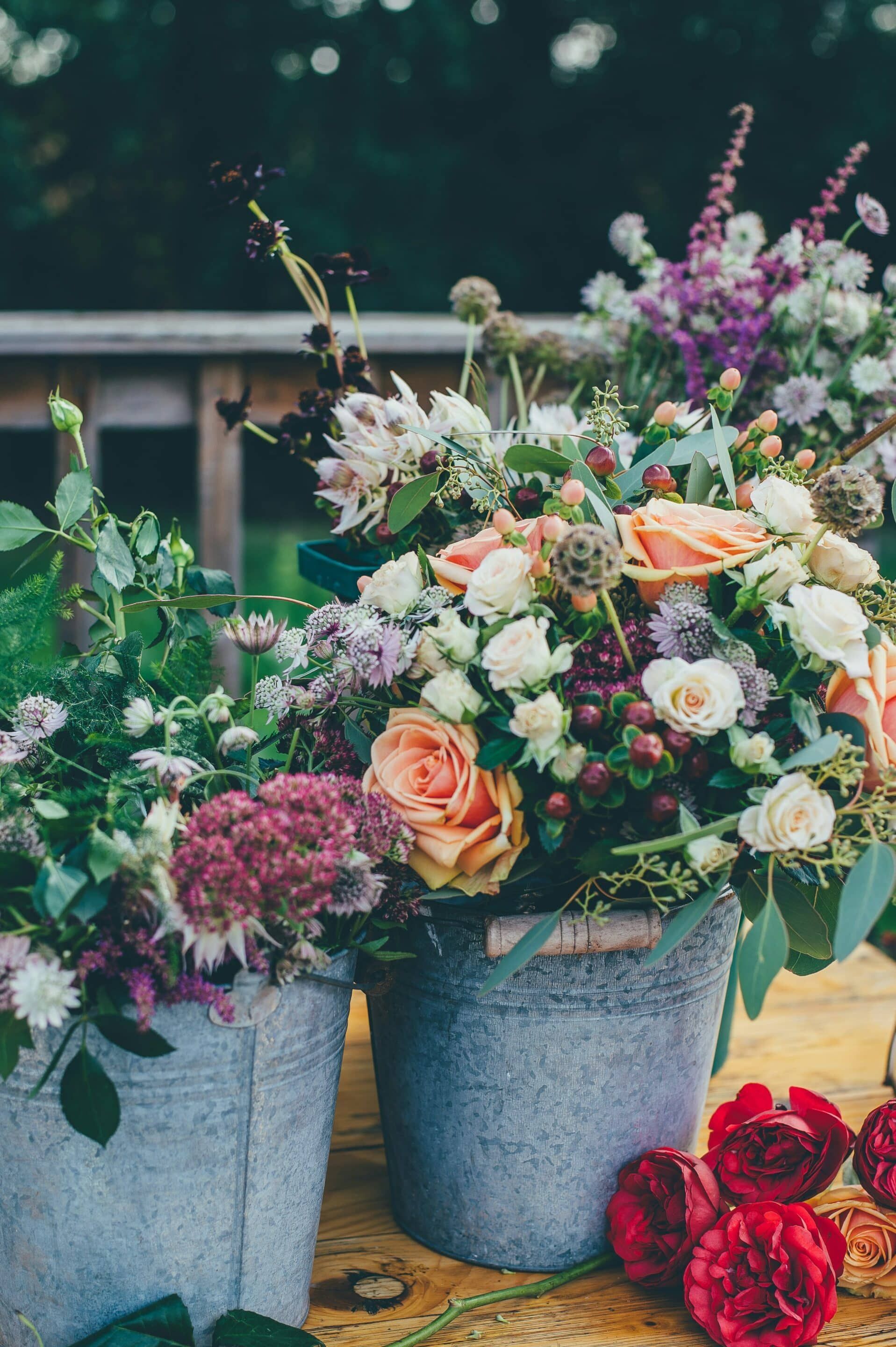 Two buckets filled with flowers are sitting on a table.