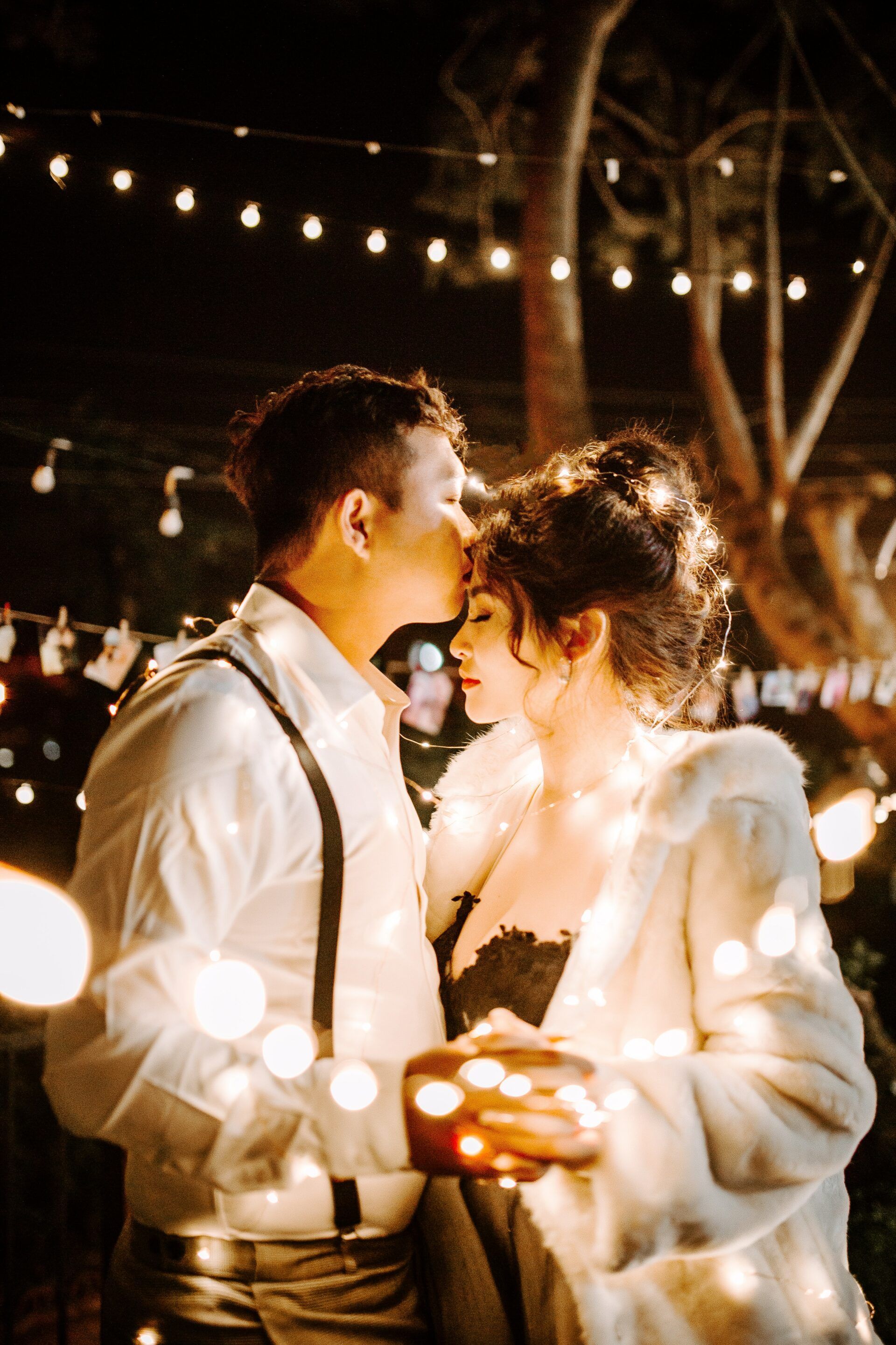 A man is kissing a woman on the forehead while holding a candle.