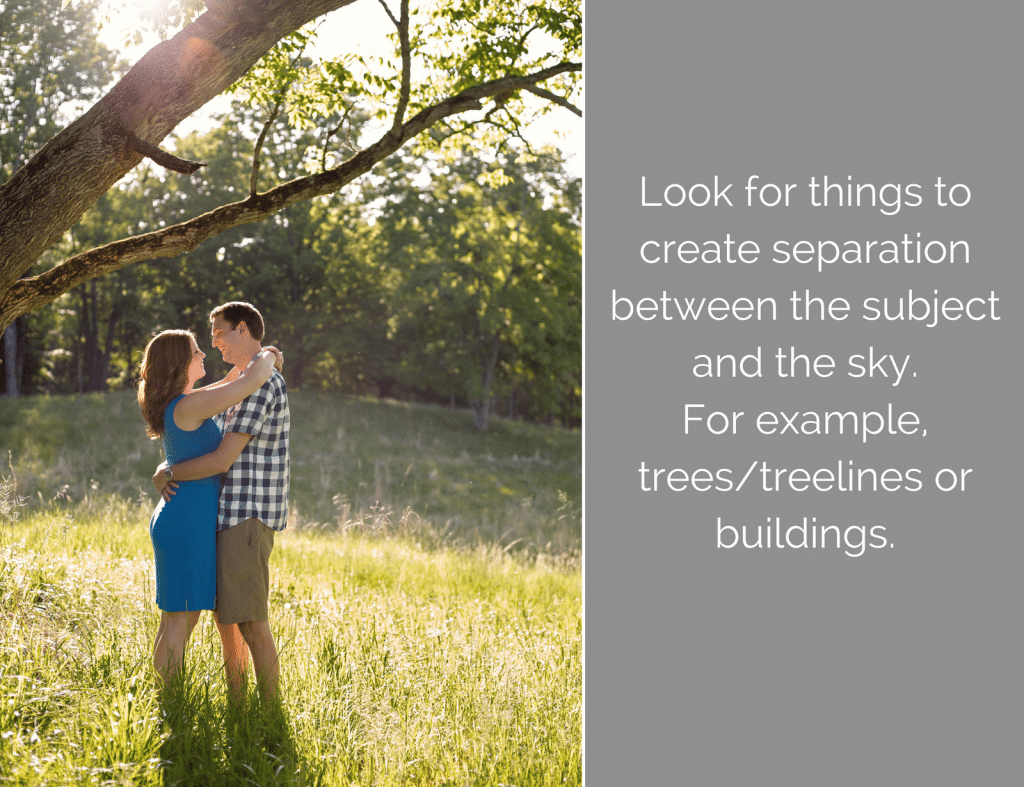 A man and a woman are hugging under a tree in a field.