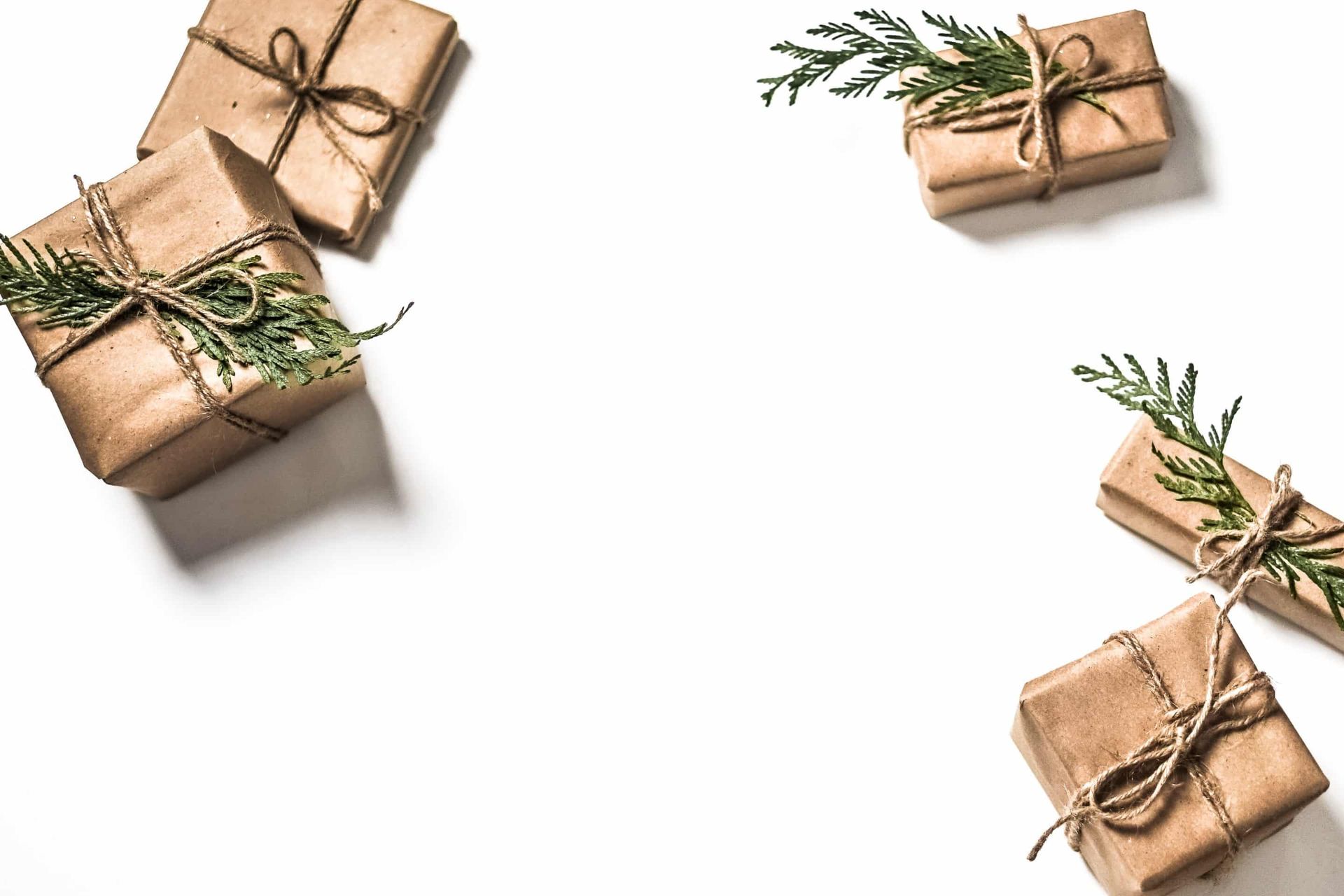 A group of gifts wrapped in brown paper and tied with string on a white background.