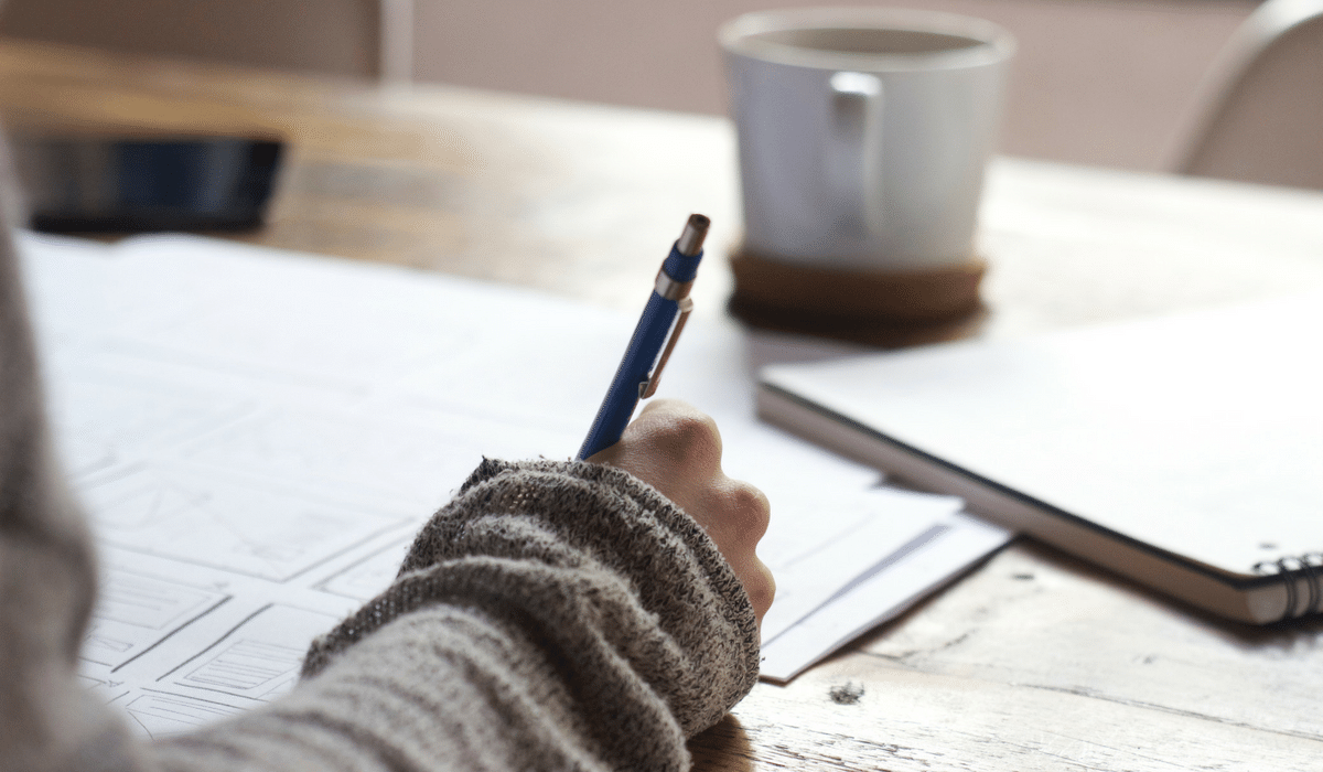 A person is writing on a piece of paper with a pen.