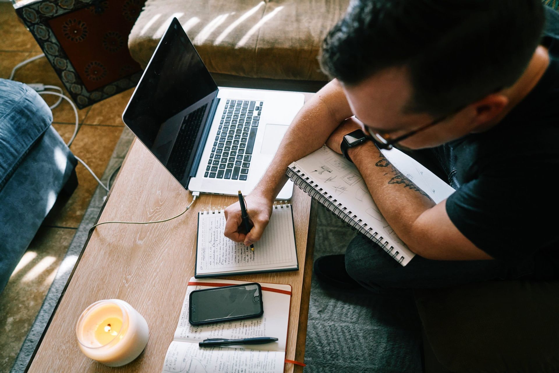 A man is sitting at a table with a laptop and a notebook.