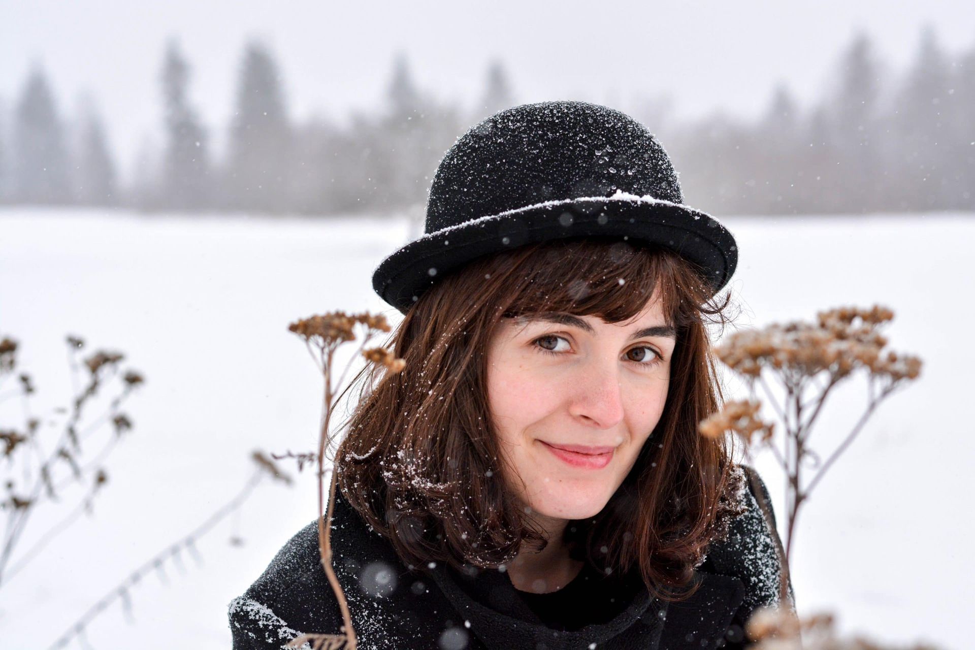 A woman wearing a black hat is standing in the snow.