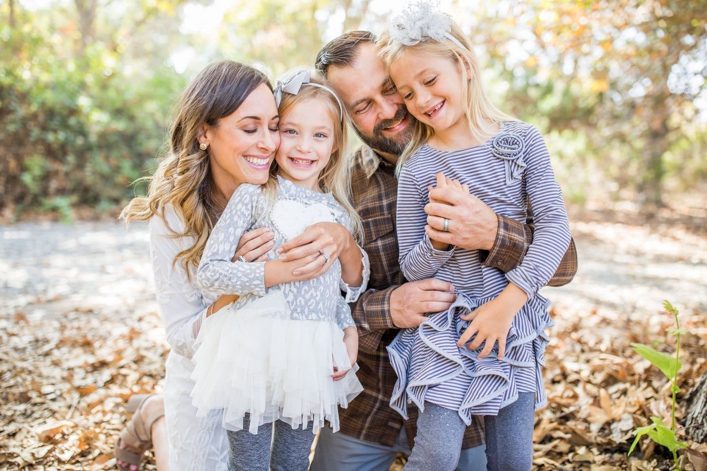 A family is posing for a picture in the woods.