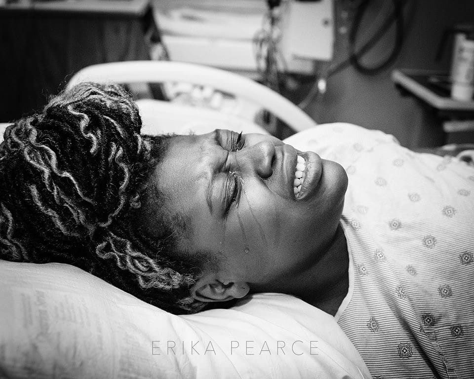 A woman is laying in a hospital bed with her eyes closed.