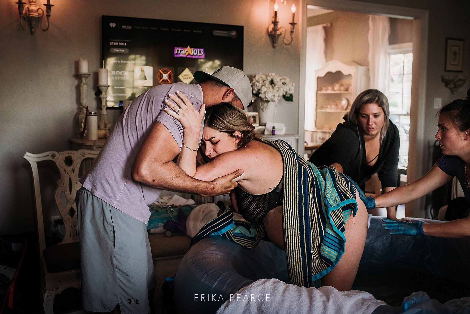 A man is hugging a pregnant woman in a living room.