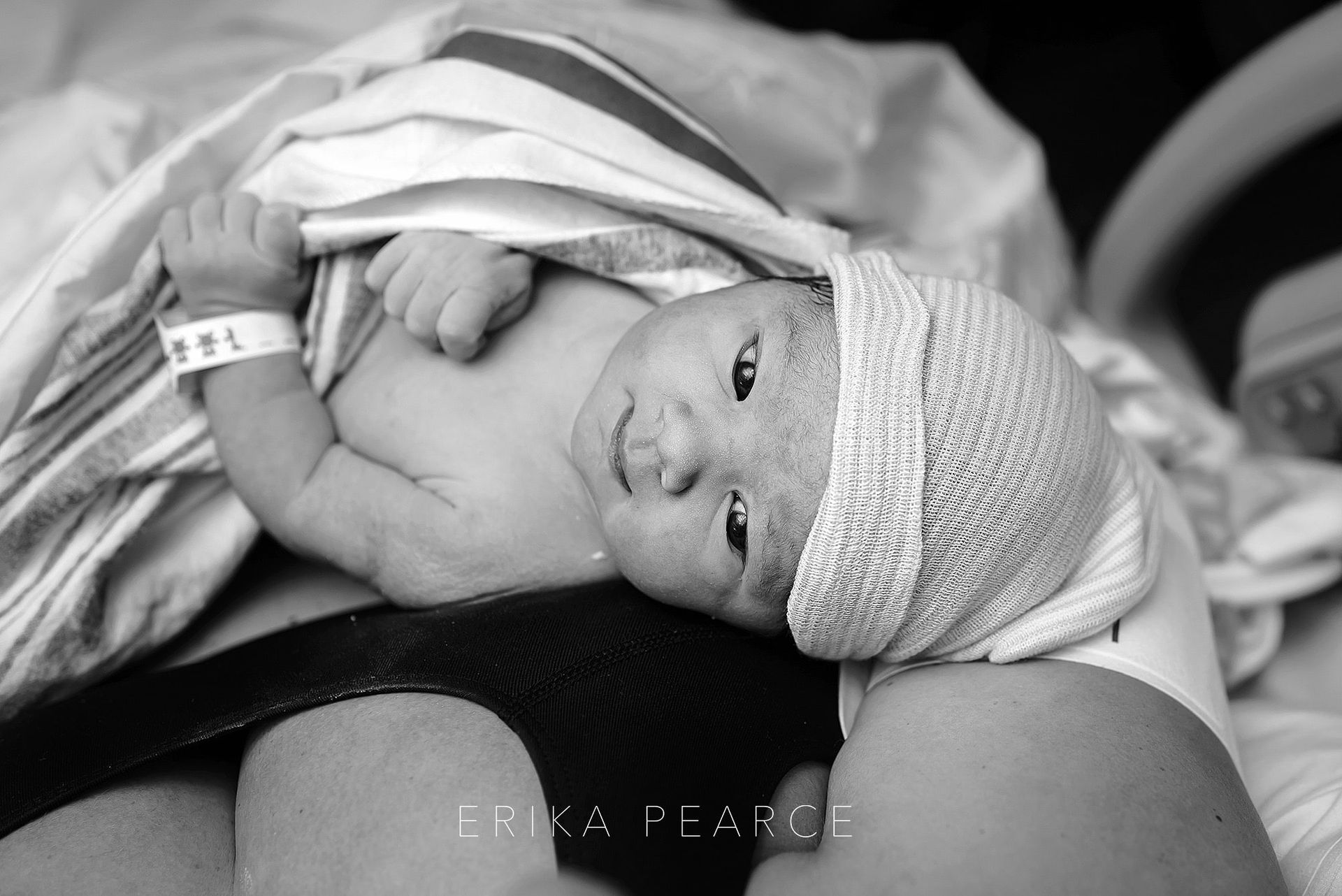 A black and white photo of a newborn baby wearing a hat