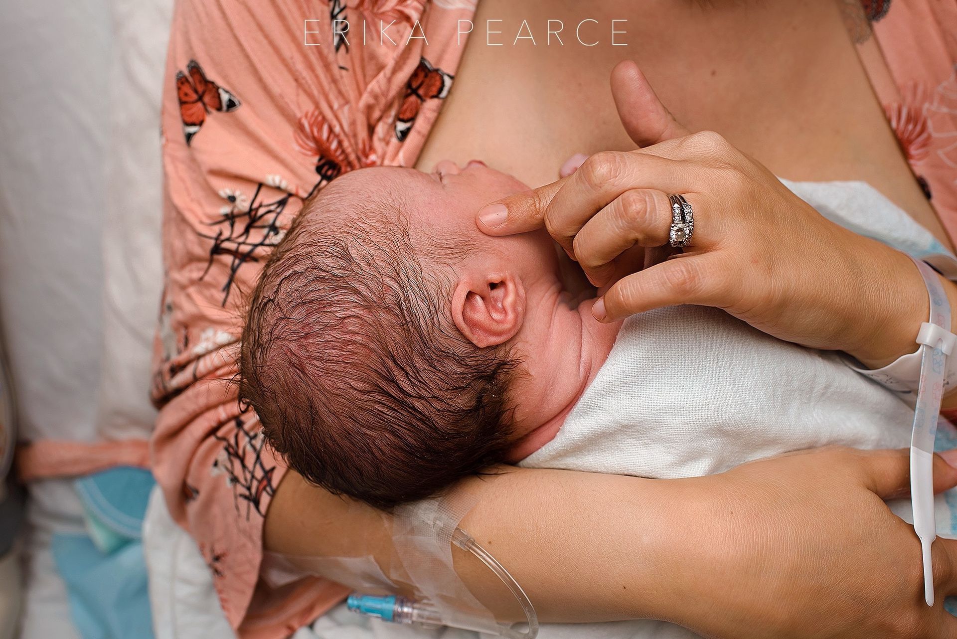 A woman is breastfeeding a newborn baby in a hospital bed.