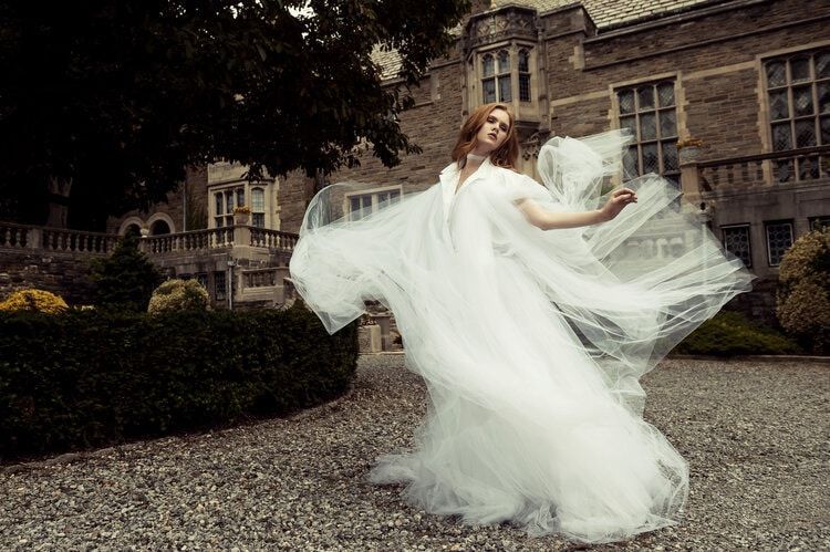 A woman in a white dress is dancing in front of a building.