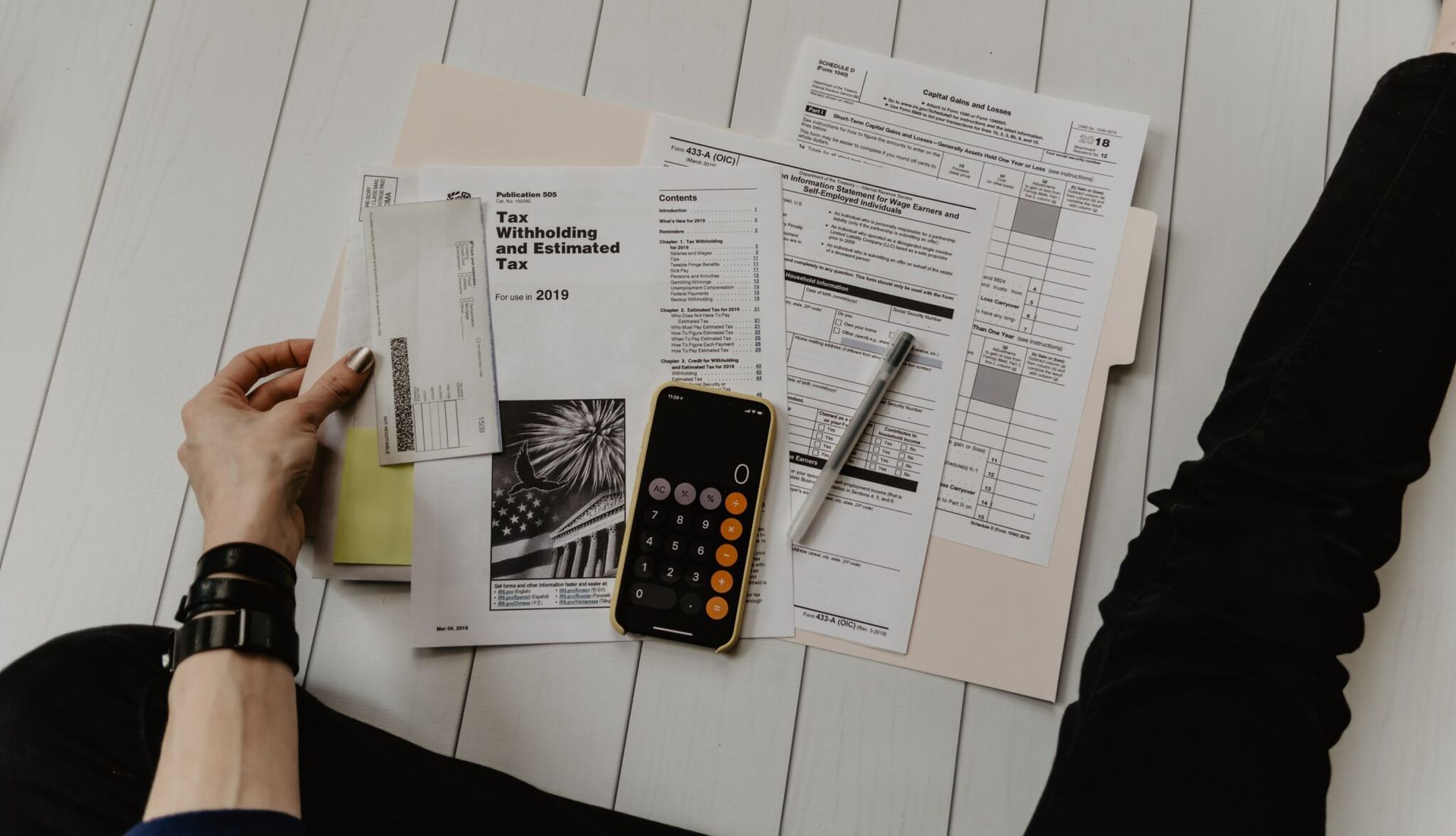 A person is sitting on the floor with papers and a calculator.