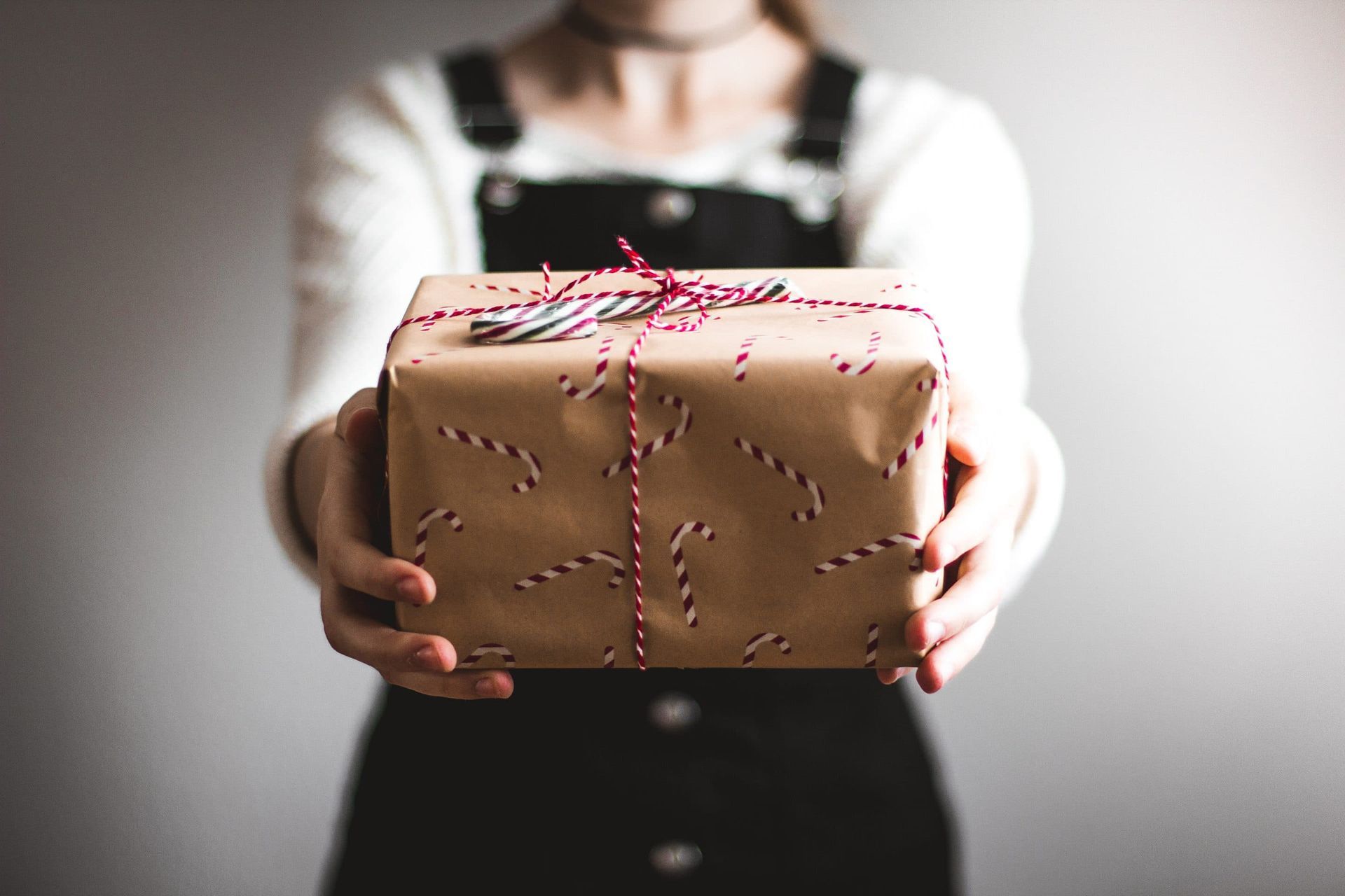 A woman is holding a wrapped gift in her hands.