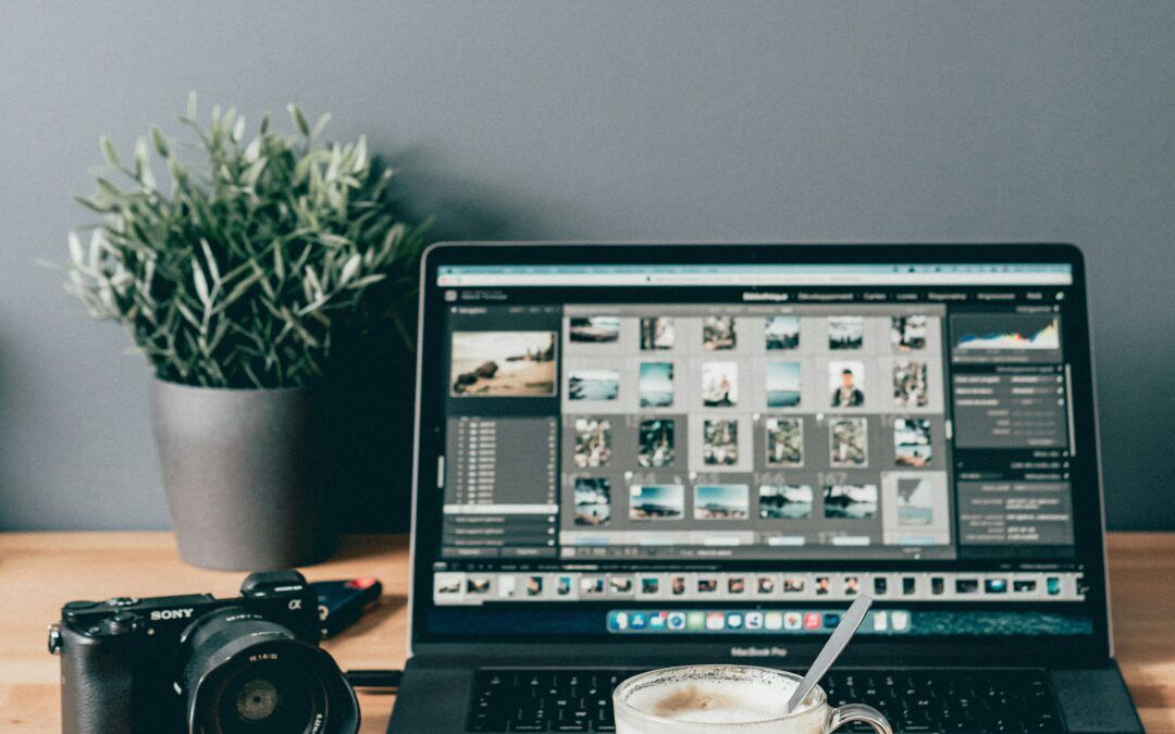 A laptop computer is sitting on a wooden table next to a camera and a cup of coffee.