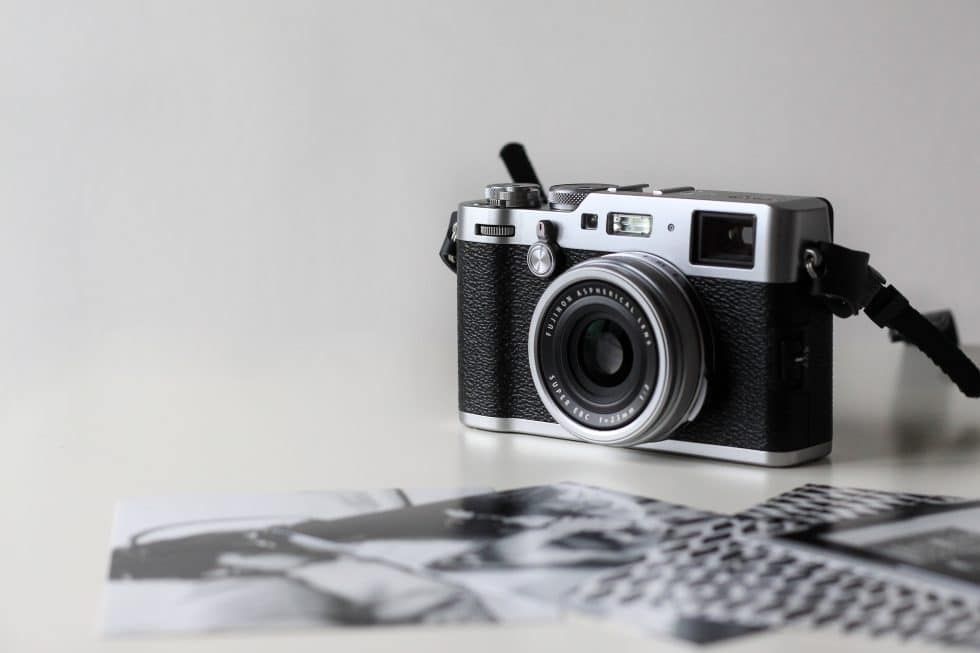 A black and silver camera is sitting on top of a white table.