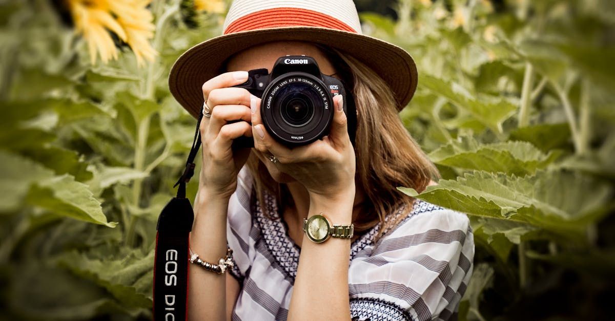 A woman in a hat is taking a picture with a camera.