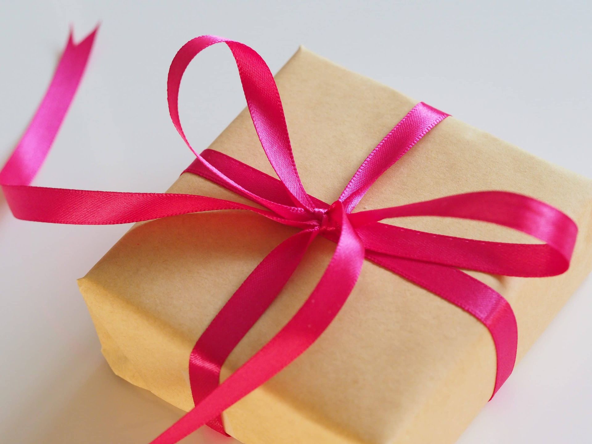 A gift wrapped in brown paper with a pink ribbon