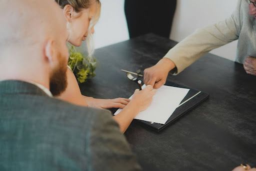 A bride and groom are signing a document at a table.