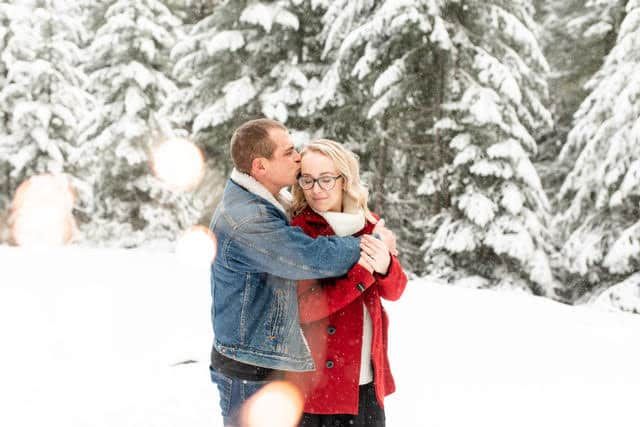 A man is kissing a woman on the cheek in the snow.