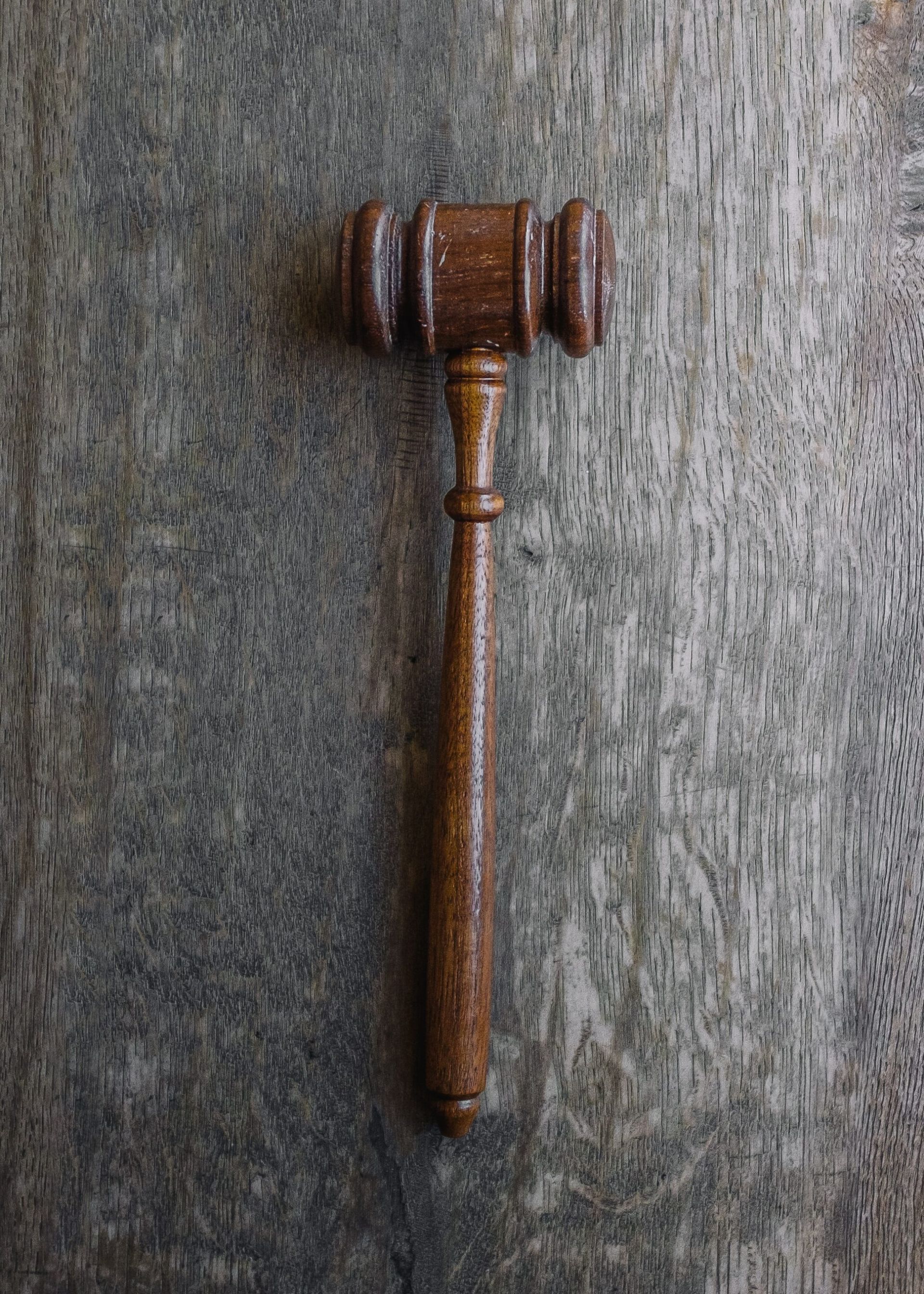 A wooden judge 's gavel is sitting on a wooden table.