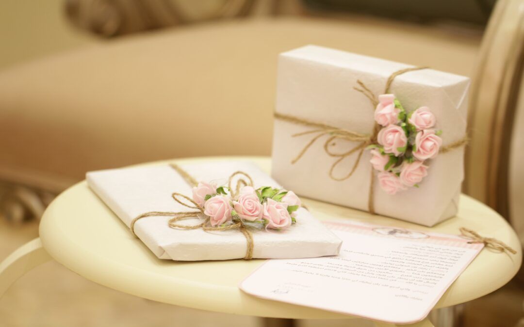 Two gifts wrapped in white paper with pink flowers are sitting on a table.