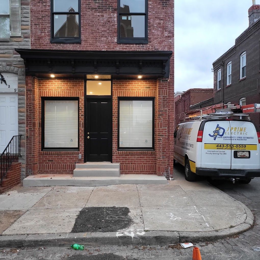 A white van is parked in front of a brick building