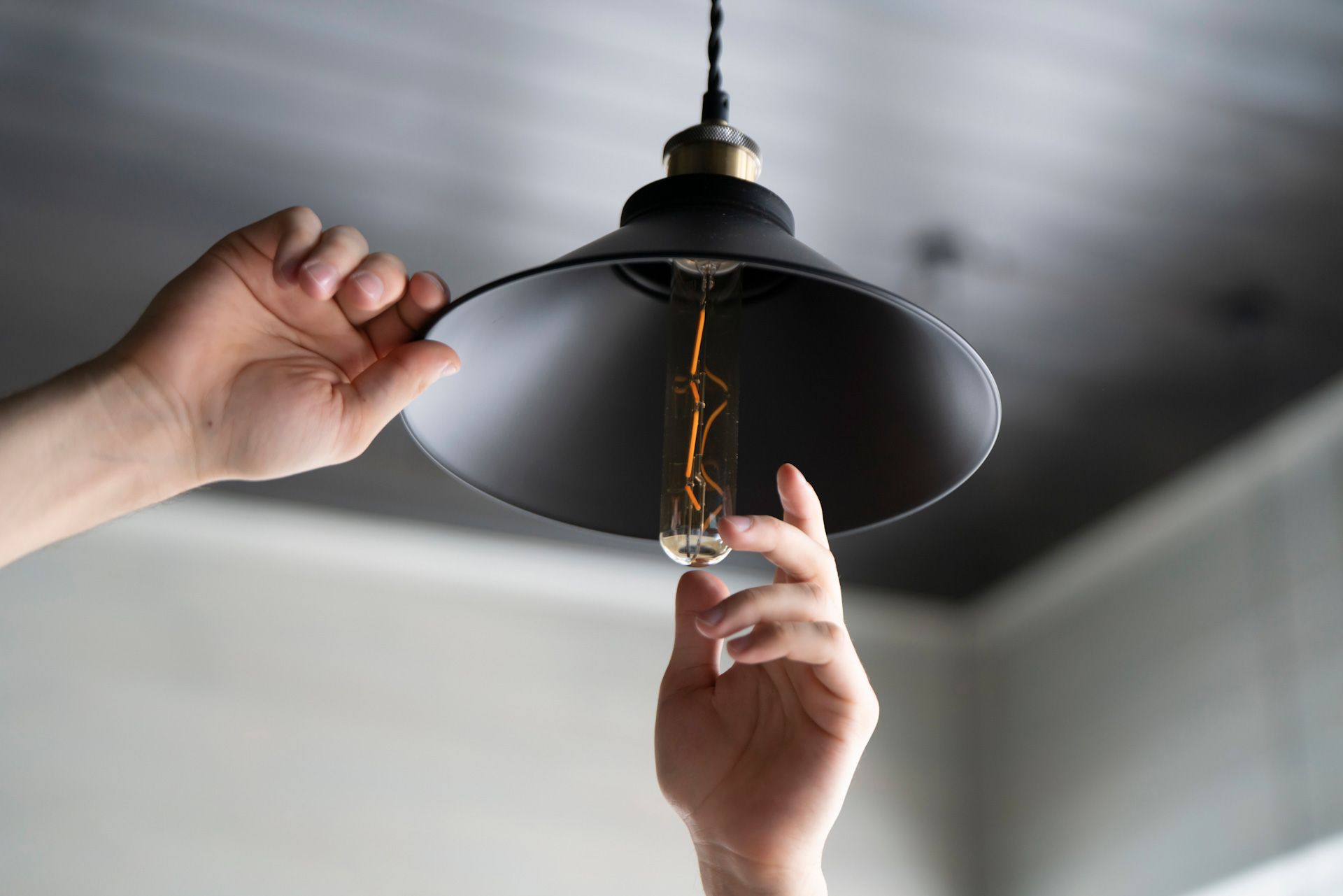 A person is changing a light bulb in a ceiling light.