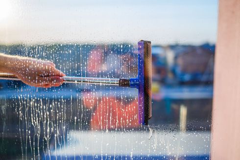 A person is cleaning a window with a squeegee.
