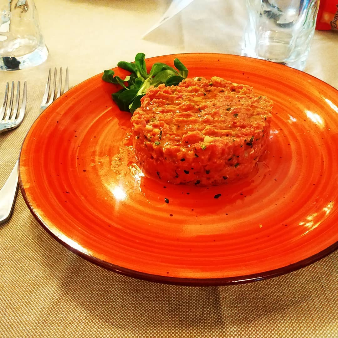 Piatto rosso con una porzione di cibo e guarnizione.