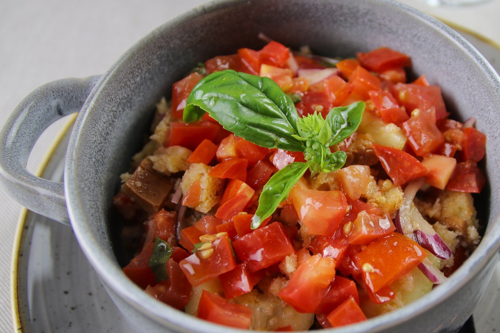 Ciotola di insalata panzanella con pomodori a cubetti, basilico e pane.