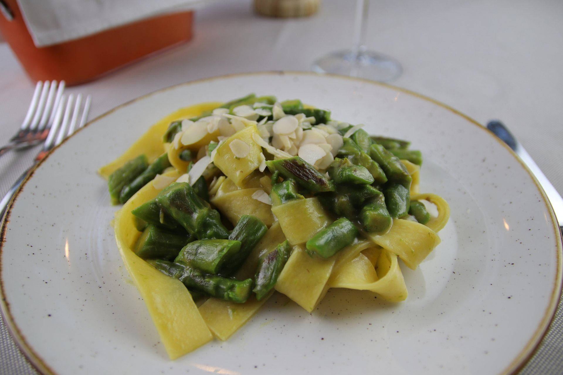 Pasta con fagiolini e mandorle su un piatto bianco.