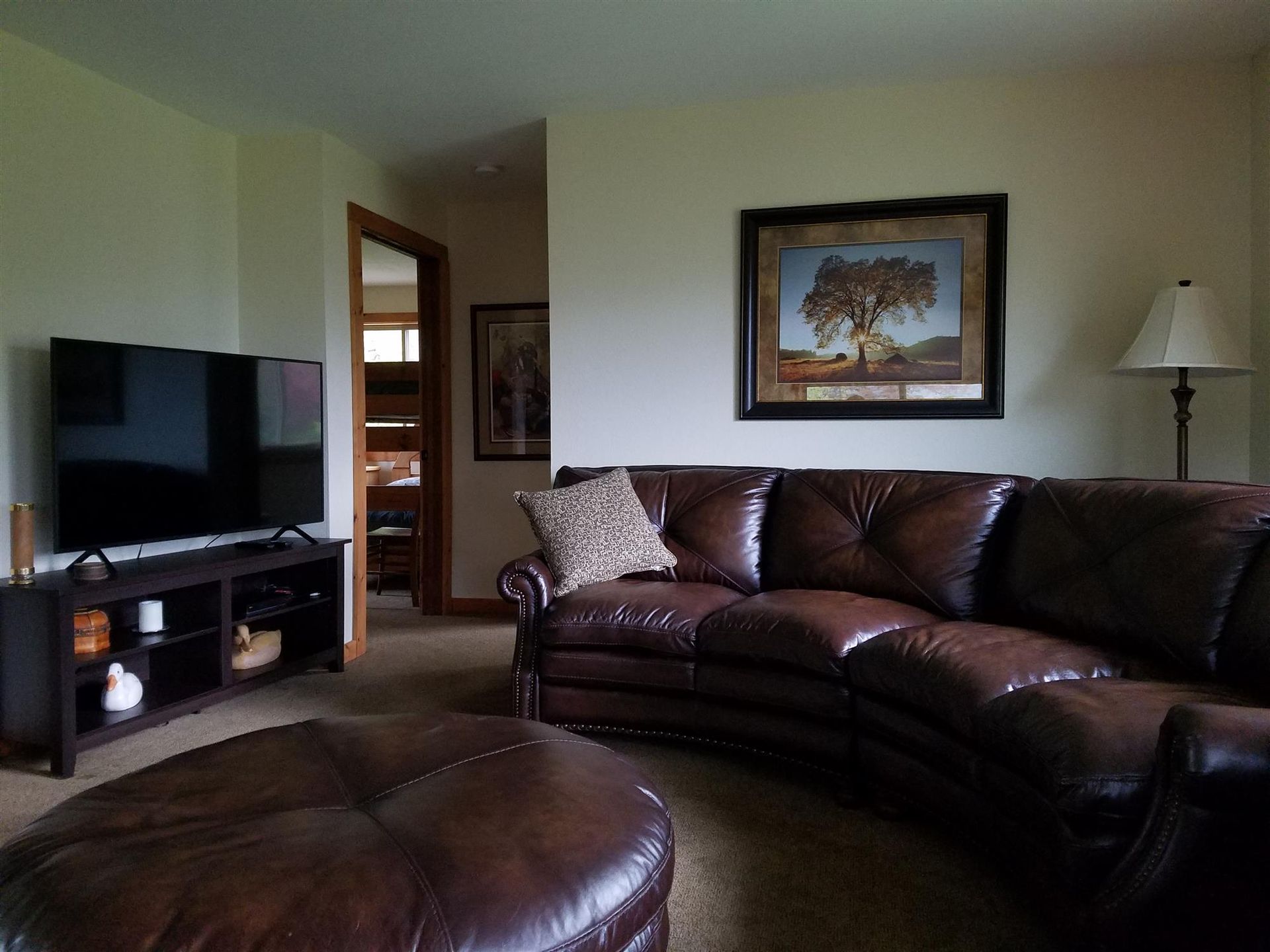 A living room with a brown leather sectional couch and a flat screen tv